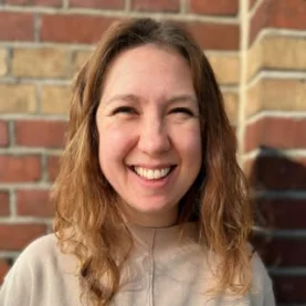 Rachael, the therapist, smiling warmly in front of a brick wall